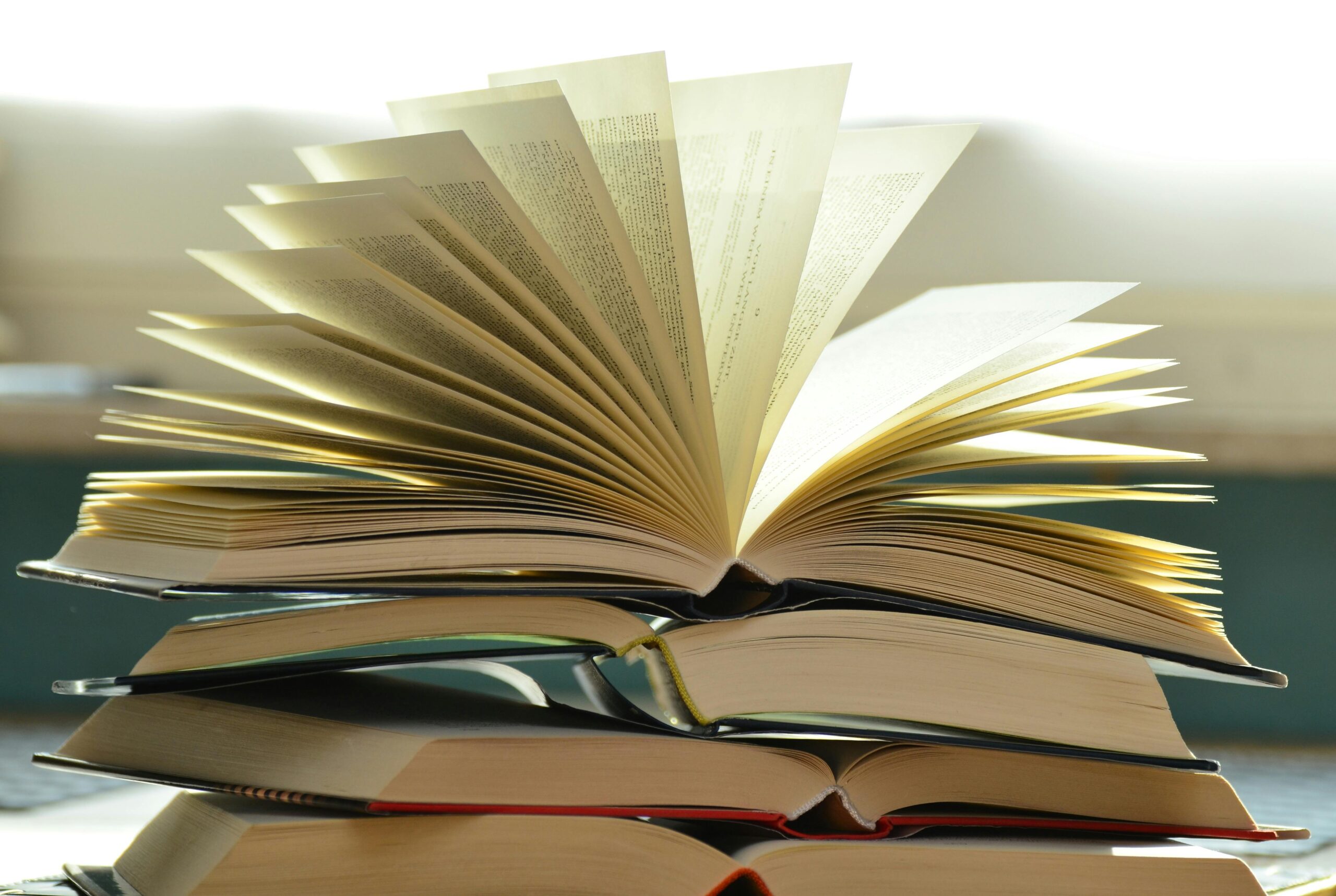 Book open, on top of pile of books.